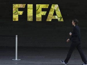 A woman walks by a logo of international soccer's top body FIFA, on May 27, 2015 at the organization's headquarters in Zurich. Swiss policeraided a Zurich hotel to detain six top football officials as part of a US investigation into tens of millions of dollars of bribes paid to sport leaders, Swiss authorities and media reports said.  AFP PHOTO / FABRICE COFFRINI        (Photo credit should read FABRICE COFFRINI/AFP/Getty Images)